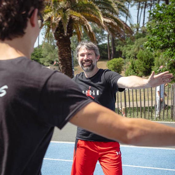 Fabien Lageyre, diététicien-nutritionniste et coach sportif à Dax et Saubrigues, souriant sur une piste d’athlétisme en réalisant des étirements avec son patient